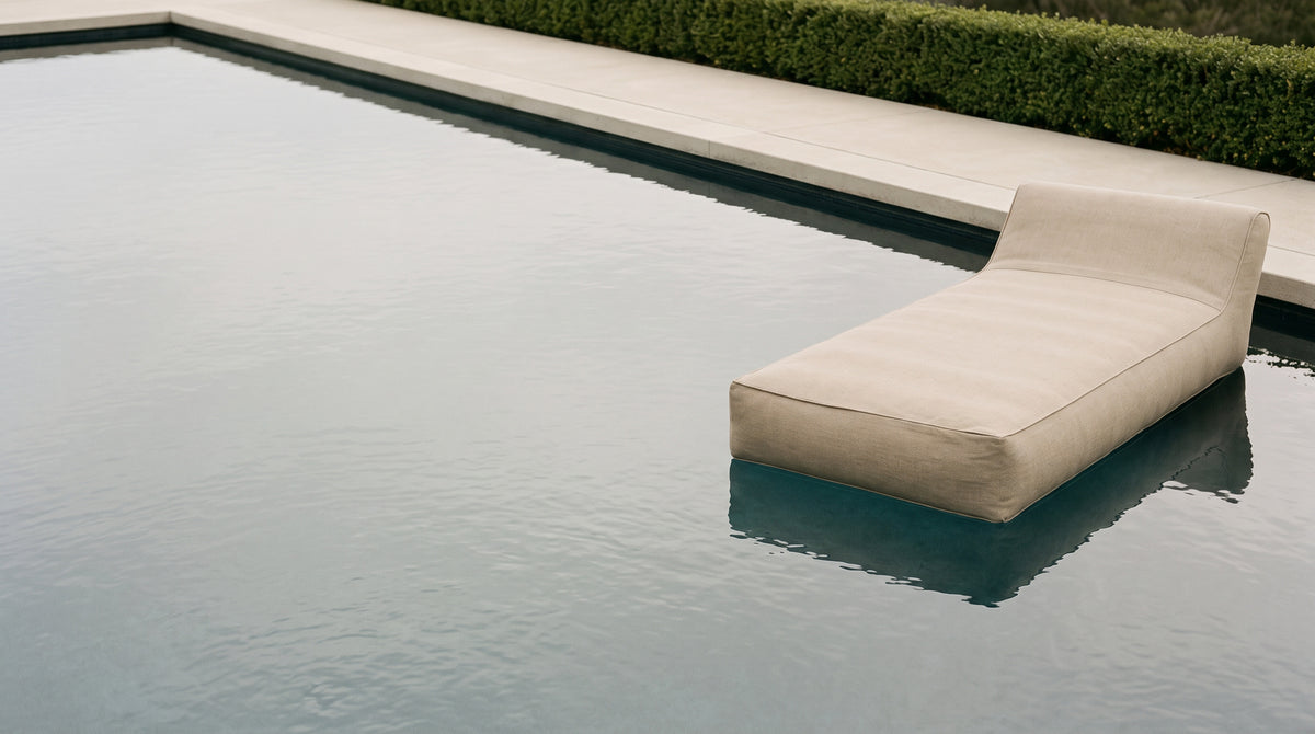 Poolboy Floata-Long in natural beige on a calm pool with open water alongside