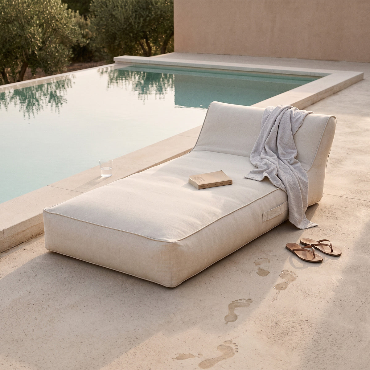 Poolboy Floata-Long in Cloud white by the pool, a towel left over it.